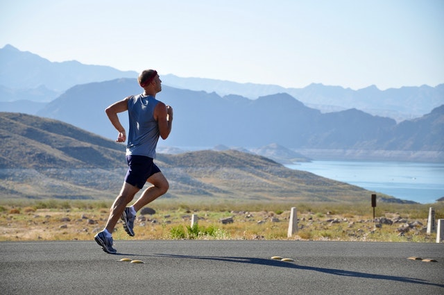 Muž v športovom oblečení beží po asfaltovej ceste.jpg